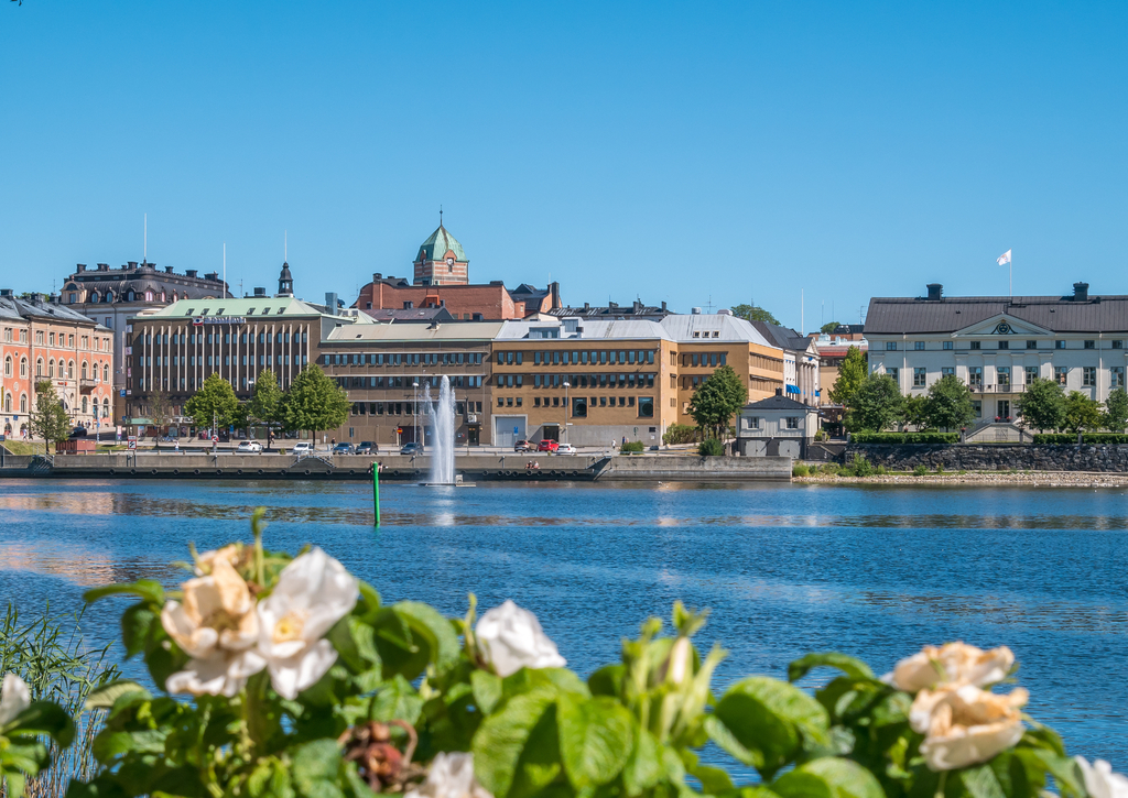 Lais Puzzle - Die Stadt Harnosand im nördlichen Teil von Schweden. Blumen und See im Vordergrund. Zentrum im Hintergrund. Sommer tagsüber - 100, 200, 500 & 1.000 Teile p-261932