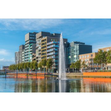 Lais Puzzle - Lelystad: Einheimische gehen und überqueren den Teich mit Brunnen in der Mitte mit modernen Geschäftsgebäuden und Häusern im Hintergrund - 2.000 Teile