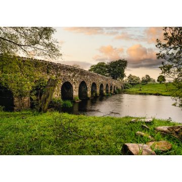 Lais Puzzle - Alte Steinbogenbrücke aus dem 12. Jahrhundert über einen Fluss, Felsen auf der ersten Ebene. Grüne Felder und Bäume. Dramatischer Himmel bei Sonnenuntergang. Grafschaft Meath, Irland - 1.000 Teile