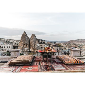 Lais Puzzle - Ein runder Tisch, Kissen und ein traditioneller Teppich auf einer Terrasse vor einer wunderschönen Kulisse von Gebäuden und Felsen in Kappadokien, Türkei - 1.000 Teile