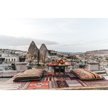 Lais Puzzle - Ein runder Tisch, Kissen und ein traditioneller Teppich auf einer Terrasse vor einer wunderschönen Kulisse von Gebäuden und Felsen in Kappadokien, Türkei - 2.000 Teile