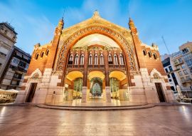 Lais Puzzle - Die majestätische Fassade des Colon-Marktes und sein Spiegelbild auf dem Boden des Platzes, aufgenommen zur blauen Stunde, Valencia, Spanien - 100, 200, 500 & 1.000 Teile