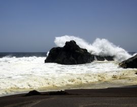 Lais Puzzle - Kraftvolle Wellen, die auf einem Felsen zusammenstoßen und Wasser in der Luft am entfernten schwarzen Lavasandstrand an der Pazifikküste spritzen - Cobquecura Piedra De La Loberia, Chile - 40 Teile