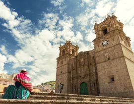Lais Puzzle - Frau mit Keperina (Tasche auf dem Rücken) auf den Stufen der Kathedrale von Puno (Peru) sitzend - 40 Teile