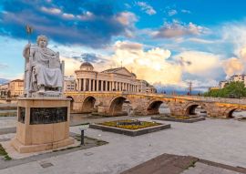 Lais Puzzle - Skopje, Nord-Mazedonien: Statue des byzantinischen Kaisers Justinian und Steinbrücke hinter dem Archäologiemuseum bei Sonnenuntergang in Skopje - 100, 200, 500 & 1.000 Teile