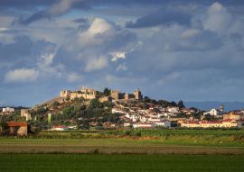 Lais Puzzle - Von der Sonne beleuchtete Burg und Häuser von Montemor-o-Velho, von den Reisfeldern aus gesehen, mit einem Himmel voller Wolken. Montemor-o-Velho in Portugal - 100, 200, 500 & 1.000 Teile