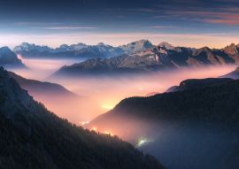 Lais Puzzle - Berge im Nebel bei schöner Herbstnacht in den Dolomiten, Italien. Landschaft mit alpinem Bergtal, niedrigen Wolken, Wald, buntem Himmel mit Sternen, Stadtbeleuchtung in der Abenddämmerung. Luftaufnahme. Passo Giau - 100, 200, 500 & 1.000...