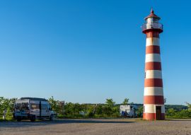 Lais Puzzle - graues Wohnmobil neben einem rot-weißen Leuchtturm an der dänischen Küste unter wolkenlosem blauem Himmel geparkt - 100, 200, 500 & 1.000 Teile
