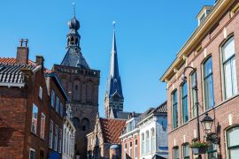 Lais Puzzle - Das Zentrum von Culemborg mit den Häusern am Varkensmarkt (Schweinemarkt), dem Turm des Binnenpoort (Stadttor) und dem Turm der St. Barbara Kirche an einem sonnigen Nachmittag. Gelderland, Die Niederlande - 2.000 Teile