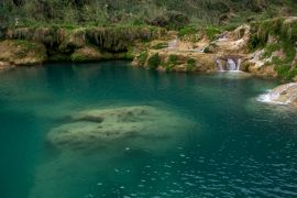 Lais Puzzle - Türkisfarbenes Wasserbecken mit Kalksteinformationen unter Wasser, umgeben von Wasserfällen im mit Farnen bewachsenen Fels, Mexiko - 2.000 Teile