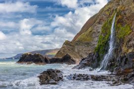 Lais Puzzle - Ein Wasserfall an der walisischen Küste in dem kleinen Fischerdorf Tresaith. Das Meer ist wild, ebenso wie der weiß-blaue Wolkenhimmel. Im Hintergrund die hohen Klippen - 2.000 Teile
