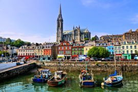 Lais Puzzle - Bunte Gebäude und alte Boote mit der Kathedrale im Hintergrund im Hafen von Cobh, County Cork, Irland - 2.000 Teile