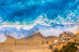 Lais Puzzle - Blick von oben auf den goldenen Strand und das leuchtend blaue Meer von Milos Beach auf der Insel Lefkada, Griechenland, mit hohen Wellen und langen Schatten während des Sonnenuntergangs im Sommer - 2.000 Teile