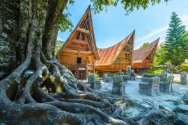 Lais Puzzle - Traditionelle Batak-Häuser in einer Reihe, Baumwurzeln im Vordergrund, orangefarbener Look. Ambarita Dorf, Toba See, Reiseziel in Sumatra, Indonesien - 2.000 Teile