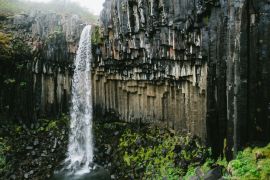 Lais Puzzle - Mächtiger Svartifoss-Wasserfall in Island unter grauem, bewölktem Himmel. Kristallklares weißes Wasser und schwarze Basaltsäulen - 2.000 Teile