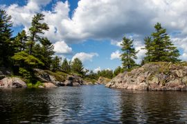 Lais Puzzle - Felsen, Bäume, blauer Himmel, weiße Wolken und Wasser an einem Sommertag am Bad River in Ontario, Kanada - 2.000 Teile