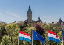 Lais Puzzle - Flaggen der Europäischen Union und Luxemburgs mit dem Bankenmuseum im Hintergrund, sonniger Tag mit blauem Himmel in Luxemburg - 1.000 Teile