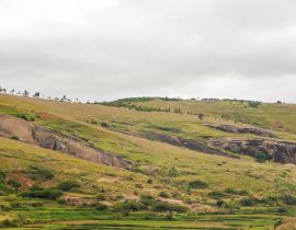 Lais Puzzle - Typische Madagaskar-Landschaft in der Region um Farariana an einem bedeckten Tag. Eher flaches Grasland mit nur wenigen Bäumen, mit einigen Felsen und Hügeln, Reisfelder im Vordergund - 40, 100, 200, 500, 1.000 & 2.000 Teile