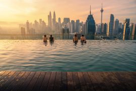 Lais Puzzle - Reisende mit Blick auf die Skyline von Kuala Lumpur im Swimmingpool auf dem Dach eines Hotels bei Sonnenaufgang in Kuala Lumpur, Malaysia - 2.000 Teile