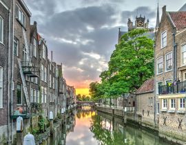 Lais Puzzle - Eine Gracht im alten mittelalterlichen Stadtzentrum von Dordrecht, Niederlande, mit Häusern auf beiden Seiten und einem orangeroten Sonnenuntergang in der Ferne - 40, 100, 200, 500, 1.000 & 2.000 Teile