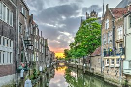 Lais Puzzle - Eine Gracht im alten mittelalterlichen Stadtzentrum von Dordrecht, Niederlande, mit Häusern auf beiden Seiten und einem orangeroten Sonnenuntergang in der Ferne - 2.000 Teile