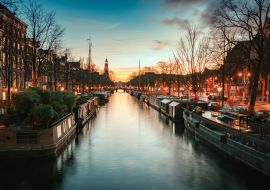 Lais Puzzle - Hausboote in der Prinsengracht im alten Zentrum von Amsterdam mit der Turmspitze des Westertoren im Hintergrund bei Sonnenuntergang - 1.000 Teile