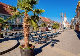 Lais Puzzle - Hauptplatz mit Palmen am Straßencafé und der katholischen Kirche St. Jakobus in der Stadt Leibnitz in der Steiermark in Österreich. Architektur des Doms - 1.000 Teile