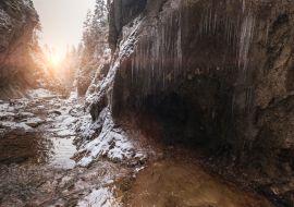 Lais Puzzle - Fließender kleiner Bach, der aus einer Eiszapfenhöhle fließt und große Felsbrocken spült. Erste Sonnenstrahlen beleuchten junge Schneeinseln. Cold frühen Winter Bergwald Landschaft in der Slowakei Tatry Berg - 1.000 Teile