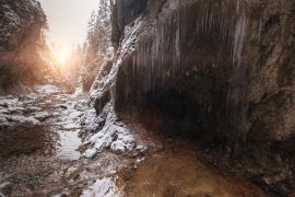 Lais Puzzle - Fließender kleiner Bach, der aus einer Eiszapfenhöhle fließt und große Felsbrocken spült. Erste Sonnenstrahlen beleuchten junge Schneeinseln. Cold frühen Winter Bergwald Landschaft in der Slowakei Tatry Berg - 2.000 Teile
