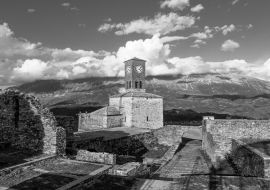 Lais Puzzle - Blick auf den Uhrenturm der Burg von Gjirokastra mit Bergen und Wolken in schwarz weiß - 1.000 Teile