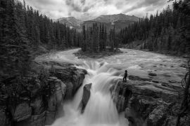 Lais Puzzle - Frau steht am Rande einer Klippe an einem wunderschönen Wasserfall in den kanadischen Rockies während eines Sommertages. Aufgenommen in Sunwapta Falls, Jasper, Alberta, Kanada in schwarz weiß - 2.000 Teile