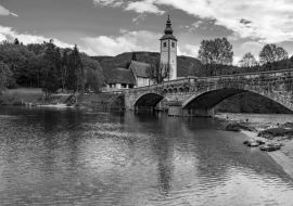 Lais Puzzle - Blick auf die Steinbrücke und die Kirche St. Johannes der Täufer am Bohinjer See, Slowenien in schwarz weiß - 1.000 Teile