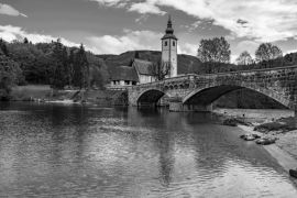 Lais Puzzle - Blick auf die Steinbrücke und die Kirche St. Johannes der Täufer am Bohinjer See, Slowenien in schwarz weiß - 2.000 Teile