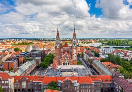 Lais Puzzle - Szeged, Ungarn - Panoramablick aus der Luft auf die Votivkirche und die Kathedrale Unserer Lieben Frau von Ungarn (Szeged Dom) an einem sonnigen Sommertag mit der Innenstadtbrücke (Belvarosi hid) und blauem Himmel und Wolken - 1.000 Teile