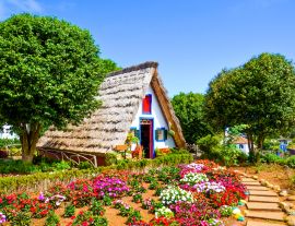 Lais Puzzle - Erstaunliche traditionelle Häuser in Santana, Madeira, Portugal. Die dreieckigen Holzhäuser sind ein Teil des portugiesischen Erbes. Vorgarten mit schönen bunten Blumen - 1.000 Teile