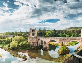 Lais Puzzle - Besalu, Girona, Katalonien, Spanien. Berühmtes Wahrzeichen, die mittelalterliche romanische Brücke von Besalu über den Fluss Fluvia an einem bewölkten Sommertag - 1.000 Teile